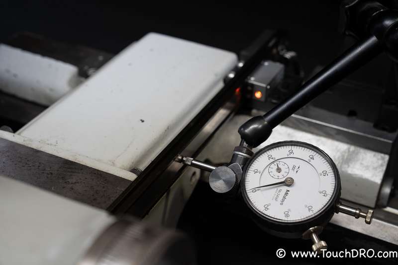 Aligning the magnetic scale with a dial indicator Dial indicator sweeping a magnetic DRO scale to check mounting alignment and head-to-strip spacing